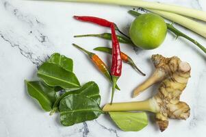 a bunch of fresh herbs and vegetables for Tomyum on a white marble counter photo