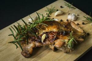 a piece of meat with rosemary and garlic on a cutting board photo