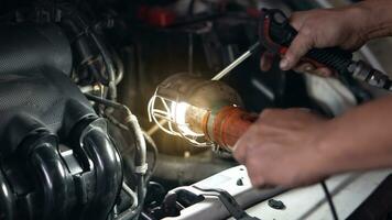 Four-cylinder engine illuminated by a maintenance torch. Car engine compartment inside dark light. with blurred hand of engineer. photo