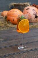 Cocktail with orange and mint on a wooden table with pumpkins photo