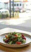 Fresco ensalada con Rúcula, Cereza Tomates, pepinos en cafetería mesa. foto