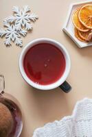 Flat lay cup and teapot with cranberry tea and plaid with snowflakes. Cozy autumn warm drink top view photo