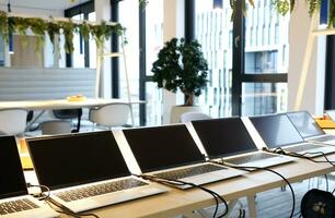 Row of laptops being prepared and set up for new employees in a company photo