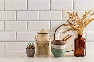 Trendy kitchen utensils and decorative vase with dry branches on stone countertop in modern kitchen interior. Front view. A copy of the space. photo