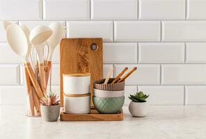 Set of eco-friendly utensils on a light kitchen countertop against a white brick wall with a copy of the space. Front view. Eco style. photo