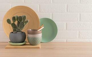 Ceramic bowls, dishes and tray on a wooden kitchen countertop, a cactus in a stylish pot in the interior of a modern kitchen space. minimalism. photo