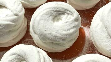 sweet apple marshmallows sprinkled with white powdered sugar on the table in a pastry shop, zoom in video