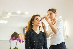 Professional hairdresser styling woman curly hair. photo