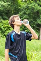 deporte hombre Bebiendo agua desde un botella. frío bebida después al aire libre aptitud física. foto