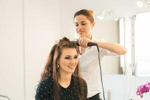 Woman at hairdresser with iron hair curler. photo