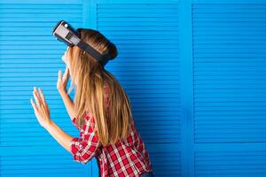 Happy woman getting experience using VR-headset glasses of virtual reality much gesticulating hands photo