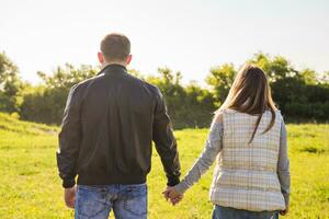 rear view of couple holding hands walking in autumn countryside photo