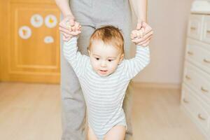 little boy first steps with the help of mother photo