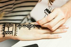 Process of applying Mehndi on female hand close up photo