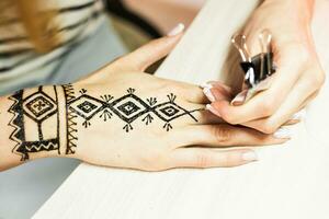 artista aplicando alheña tatuaje en mujer manos. mehndi es tradicional indio decorativo Arte. de cerca foto