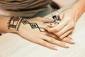 artista aplicando alheña tatuaje en mujer manos. mehndi es tradicional indio decorativo Arte. de cerca foto
