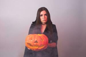 Halloween witch holding a orange pumpkin Jack o Lantern with smoke photo