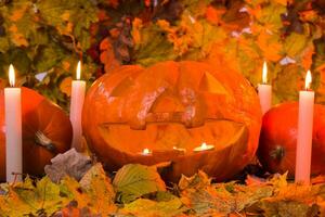 Víspera de Todos los Santos calabaza linterna con seco hojas y velas foto