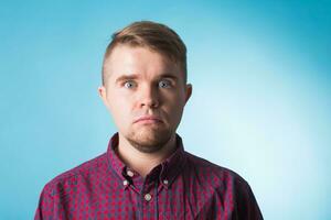 Young handsome man wearing casual shirt standing over isolated blue background skeptic and nervous, disapproving expression on face with crossed arms. Negative person. photo