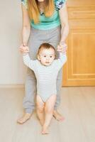 little boy first steps with the help of mother photo