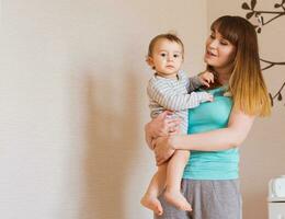 Happy mother holding a young son in the bedroom photo