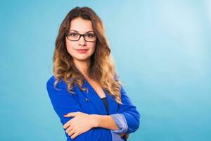 Nice young positive girl in blue jacket posing on a blue background. Happy young woman concept. photo