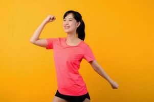 Portrait beautiful young asian sports fitness woman happy smile wearing pink sportswear posing exercise training workout isolated on yellow studio background. wellbeing and healthy lifestyle concept. photo