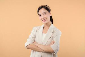 Studio portrait of happy successful confident young asian business woman. Beautiful young lady in white jacket smiling at camera standing isolated on solid beige colour copyspace background photo