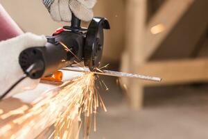 Heavy industry worker cutting steel with angle grinder photo