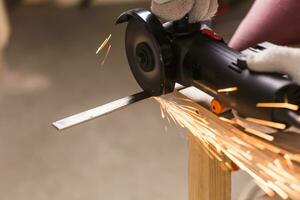 Worker Using Angle Grinder in Factory and throwing sparks. photo