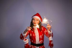 Young santa claus woman in red christmas or new year coat and hat holding sparkler and bengal fire. photo