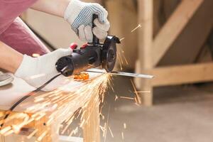 Worker Using Angle Grinder in Factory and throwing sparks. photo