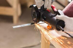 Heavy industry worker cutting steel with angle grinder photo