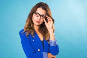 Nice young positive girl in blue jacket posing on a blue background. Happy young woman concept. photo