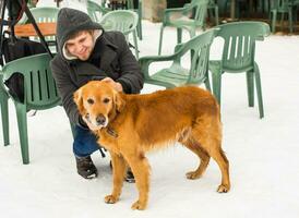 Man is playing with his yellow labrador retriever in winter landscape photo