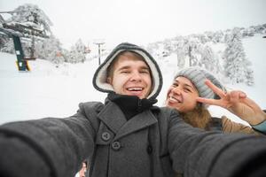 joven hombre y mujer tomando un selfie en invierno utilizando inteligente teléfono. foto