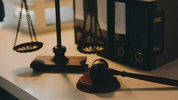 Business and lawyers discussing contract papers with brass scale on desk in office. Law, legal services, advice, justice and law concept picture with film grain effect video