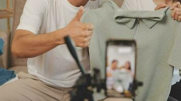 joven asiático mujer negocio propietario a Moda Tienda utilizando Teléfono móvil En Vivo transmisión para rebaja Moda sombrero y ropa. influencers grabar vídeo revisión articulo para vender en social medios de comunicación. en línea compras video