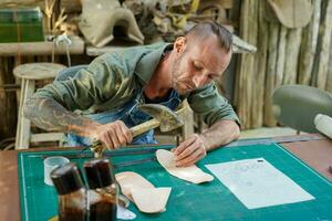 Closeup and crop leather craftsman is carefully to make a leather product with special hammer made from ox horns. Leather craftsman concept. photo