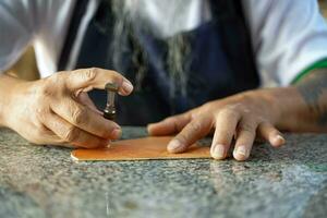 Closeup hand of leather craftsman is carefully to make a leather product for a customer., Leather craftsman concept. photo