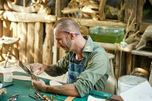 Closeup leather craftsman check and talking chat with customer for orders in her online shop with tablet at leather workplace. photo