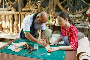 Team of leathers maker is drawing a design on leather in leather workshop. photo