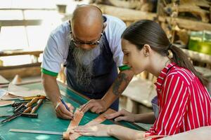 Team of leathers maker is drawing a design on leather in leather workshop. photo