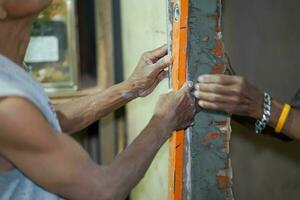 Closeup and crop builder checking wall's vertically with a level tube at construction site. photo