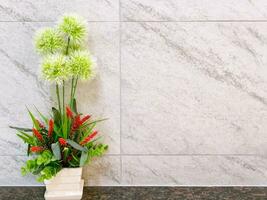 Ornamental plants in a ceramic vase on black marble shelves and marble pattern tile background with space for texts. photo