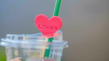 Closeup and crop clear plastic glass with pink heart on blurred background. photo