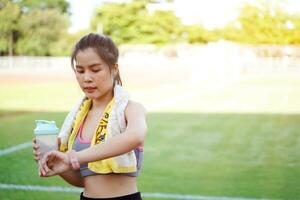 Closeup young female looking at smart watch after jogging at the football stadium. photo