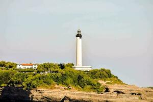 un faro en parte superior de un acantilado con un blanco casa foto