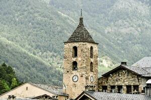 a church tower with a clock on top in the mountains photo