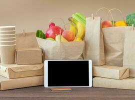 Packages with food and tablet screen with credit cards photo